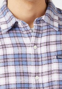 Geruit overhemd met knopen in blauw, lavendel en wit, gemaakt van zacht materiaal met een spitse kraag en een klein logoplaatje.