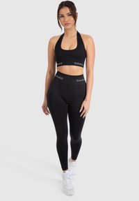 Set di reggiseno sportivo e leggings neri, con design corto, cintura elastica con logo "SMIL2" e tessuto morbido e elastico.