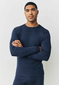 Marineblaues, langärmeliges, geripptes Thermoshirt mit Rundhalsausschnitt. Verfügt über eng anliegende Ärmel und eine lockere Passform. Glatte Textur mit minimalen Details.