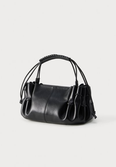 Μαύρη δερμάτινη τσάντα χειρός με μαζεμένες πλευρές, ανθεκτική πλεκτή λαβή και δύο κορδόνια για κλείσιμο, παρουσιασμένη σε ουδέτερο φόντο.