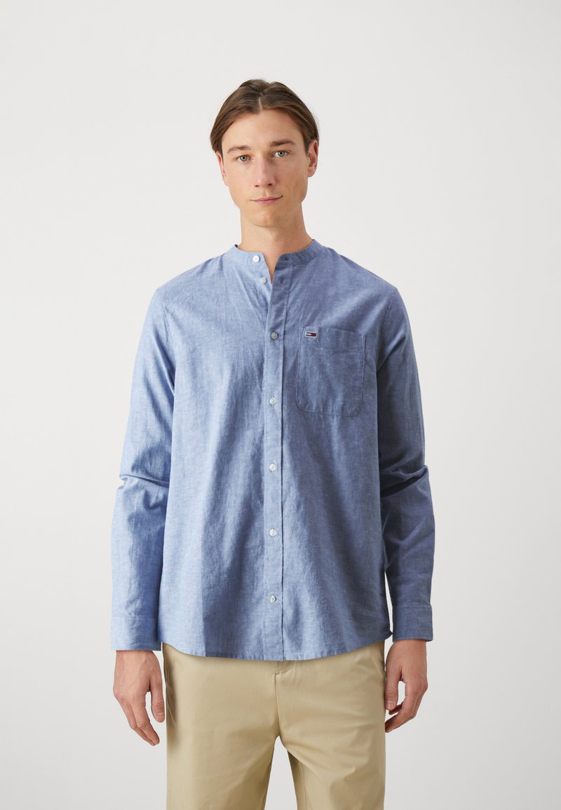 Camisa de botones azul claro con cuello mao, bolsillo en el pecho y mangas largas; fabricada en un tejido texturizado, diseñada para un ajuste casual.