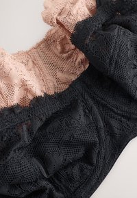 Komplet čipkaste donjeg rublja s kontrastnim bojama: nježno ružičastom i duboko crnom. Detaljni cvjetni uzorci, teksturirani materijali i rubovi s volanima.