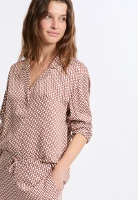 Koszula na guziki z długim rękawem w geometryczny wzór w kolorze różowo-białym, wykonana z miękkiej tkaniny o luźnym kroju z kieszenią na piersi.