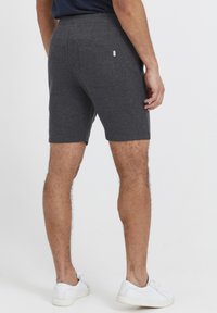 Shorts en mélange de coton gris avec une taille mi-haute, au design ajusté et une poche arrière unique. Associés à des baskets blanches.