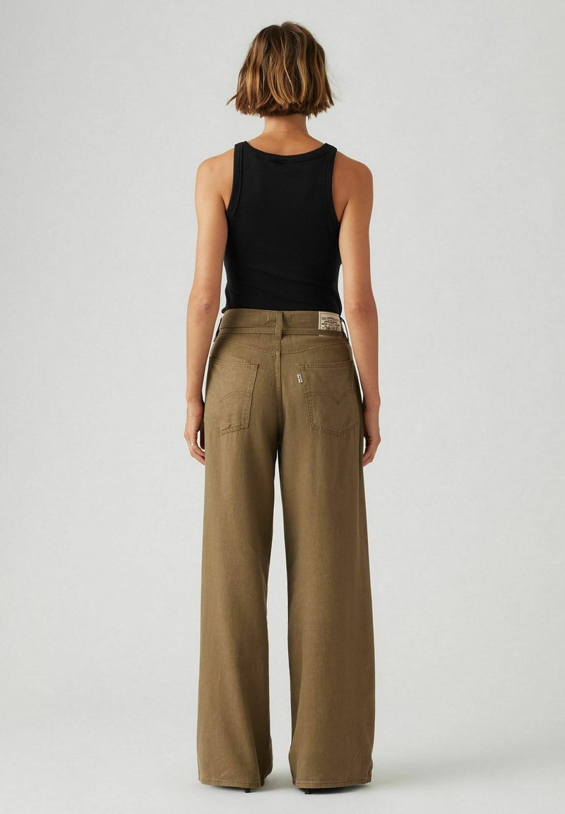 Pantalons khaki à jambes larges en tissu doux, avec une taille haute, des poches arrière et une discrète étiquette de marque sur la ceinture.