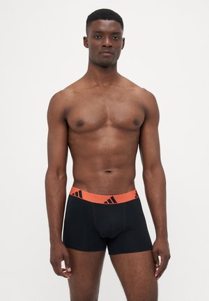 Sorte boxer briefs med en orange linning, som har sorte logo-detaljer. Blødt, strækbart materiale designet til komfort.