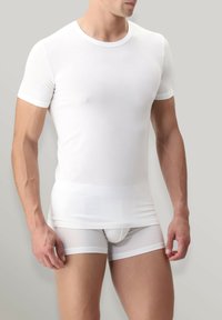 T-shirt bianco a maniche corte realizzato in tessuto liscio, design aderente, con colletto rotondo e cuciture minime, abbinato a boxer bianchi.