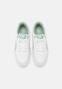 White sneakers with a mint green accent, featuring a smooth leather upper, rounded toe, lace closure, and perforated details for breathability.