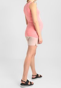 Maternity tank top in pink with white stripes, paired with light pink shorts. Black sandals with white soles. Smooth fabric and casual fit.