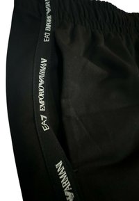 Shorts neri in cotone con una cinta in vita testurizzata. La cinta presenta un marchio stampato bianco: "EA7 EMPORIO ARMANI." Tessuto morbido.