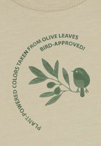 Beige katoenen stof met groene grafiek van een vogel en een olijfboomtak. De tekst luidt: "Plantenkrachtige kleuren ontleend aan olijfbladeren."