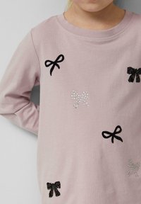 Hemd aus hellrosa, langärmeligem Stoff, dekoriert mit schwarzen und silbernen Schleifen sowie Strass-Akzenten, aus weichem Material mit Rundhalsausschnitt.