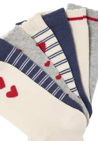 Six folded socks in cream, navy, and gray with patterns including hearts, stripes, and solid colors arranged in a fan shape.