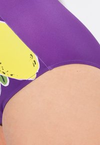 Lila baddräkt underdel med en gul citron grafik och gröna detaljer, med en slät textur och kontrasterande sömmar.