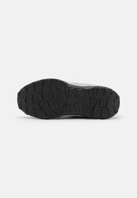 Semelle extérieure en caoutchouc noir avec des profondeurs pour une meilleure traction. Zones de talon et de orteils renforcées. Dessus gris lisse avec des accents de design minimalistes.