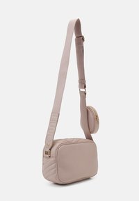 Gaiši rozā crossbody soma, kas izgatavota no mīksta materiāla. Tam ir kviltota dizaina, regulējama siksna un pievienota apaļa rāvējslēdzēja kabata.