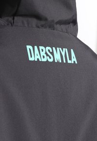 Czarna kurtka z napisem 'DABSMYLA' w wyrazistym, aqua kolorze na plecach. Materiał jest gładki, o matowym wykończeniu, a szwy są starannie zszyte.