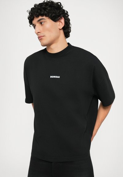 Zwarte oversized t-shirt van katoen, met een ronde halslijn en korte mouwen. De voorkant heeft een wit "Bonsai" logo.