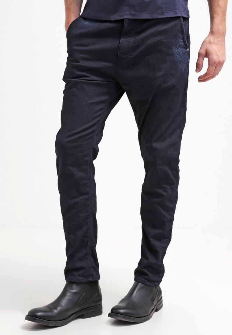 Pantaloni blu navy a gamba stretta in tessuto morbido con una leggera lucentezza, dotati di tasche laterali e abbinati a stivaletti in pelle nera.