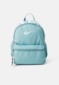 Šviesiai mėlynas Nike kuprinė su apvaliu viršumi, reguliuojamais diržais, priekinė zip kišenė ir „JUST DO IT“ etikete. Pagaminta iš patvarios medžiagos.