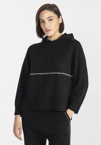 Czarna, oversize'owa bluza z kapturem z ribbowym wykończeniem u dołu i na mankietach, z ukośnym srebrnym paskiem na klatce piersiowej. Miękka dziana tekstura.