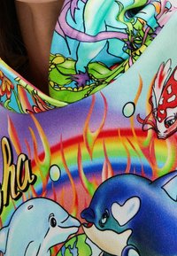 Tissu coloré et extensible présentant un design vibrant sur le thème de l'océan avec deux dauphins, des poissons et un arc-en-ciel, sur un fond texturé.