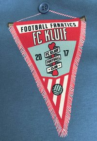 Rood en teal geborduurd clublogo op een blauwe stof, met een vlagvorm, tekst en een voetbalsymbool met gestreepte accenten.