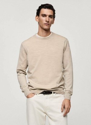 Beige trui met ronde hals, gemaakt van gebreide stof, met lange mouwen en een geribbelde rand. Draagt met witte broek en een zwarte riem.