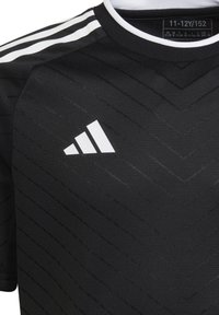 Maglia sportiva nera con un motivo testurizzato a zigzag, logo Adidas bianco sul petto e strisce bianche sulle spalle.