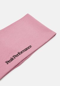 Rosa huvudband gjort av stretchigt tyg med en slät textur. Har "PeakPerformance"-logotypen i svart på ena sidan.