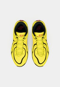 Φωτεινά κίτρινα αθλητικά παπούτσια με μαύρες λεπτομέρειες, με λείο συνθετικό επάνω μέρος, επενδεδυμένο κολάρο και αντίθετα κορδόνια.