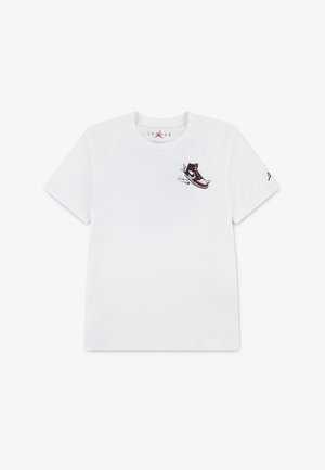 T-shirt en coton blanc avec un motif de basket en rouge et noir, situé sur le côté gauche de la poitrine. Manches courtes et encolure ras du cou.