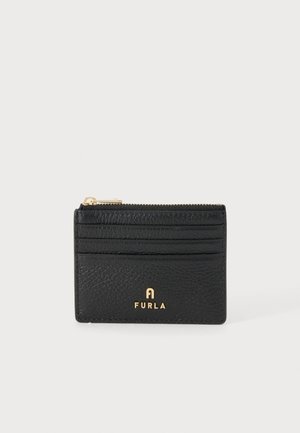 Porte-cartes en cuir noir texturé avec logo Furla doré, trois emplacements pour cartes et une pochette zippée supérieure sur un fond clair uni.