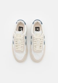Sneakers atletici bianchi con accenti in suede beige e blu, punte perforate e lacci piatti beige. Presenta il logo sulla linguetta.