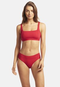 Czerwony komplet bikini, składający się z topu braletki z kwadratowym dekoltem i grubymi ramiączkami oraz pasujących majtek o wysokim stanie. Gładka, jednolita tekstura materiału.