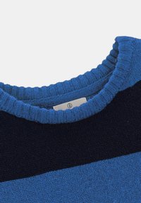 Gros plan d'un col rond sur un pull en tricot avec des rayures horizontales bleues et bleu marine.