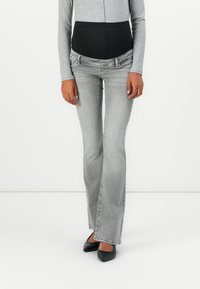 Jeans grii cu evazare, având un brâu negru închis, prezentând decolorare ușoară și două buzunare frontale. Materialul este denim cu o textură netedă.