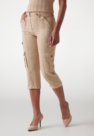 Beige Cargo-Caprihosen mit Seitentaschen, Reißverschluss und Kordelzugverschluss sowie umgeschlagenen Säumen, aus leichtem Stoff gefertigt.