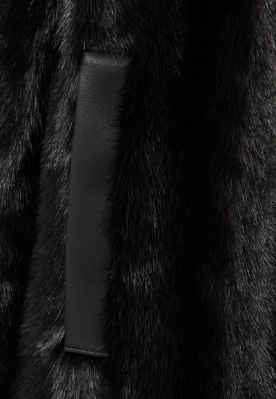 Tessuto in pelliccia sintetica nera con un accento in pelle nera liscia. La pelliccia ha una texture lucida, con lunghezze e densità variabili nel corso del tessuto.