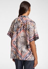 Top a maniche corte stampato con un motivo vivace nei colori rosa, blu e navy. Presenta una vestibilità comoda e un collo rotondo. Tessuto leggero.