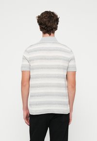 Camisa polo a rayas grises y blancas con cuello, mangas cortas y aberturas laterales, hecha de una tela ligera con una textura suave.