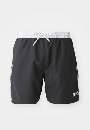 Black swim shorts with an elastic waistband, white drawstring, and side accents. Features "BOSS" logo in white on the lower leg. Smooth texture.
