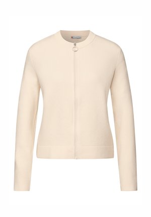 Cardigan beige chiaro, realizzato in tessuto morbido, presenta una scollatura rotonda, maniche lunghe e una chiusura frontale con zip e cursore circolare.