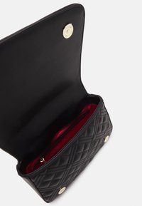 Svart kviltat läderclutch med öppen klaff, guldknappsstängning och synlig röd inredning med ett dragkedjefack.