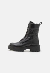 Botas de meia-cala preta feitas de couro liso, com sola elevada, bico redondo, atacadores à frente e aba na traseira.