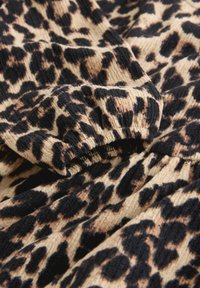 Leopardprintstof i beige og sorte nuancer. Teksturen er ribbet med en blød, luksuriøs fornemmelse og elastiske detaljer.