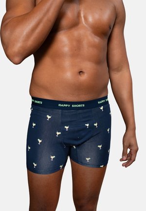 Herrentorso trägt marineblaue Boxer-Shorts mit kleinen Cocktailsglas-Motiven und einem Bund, der mit hellgrünen Buchstaben "HAPPY SHORTS" beschriftet ist.