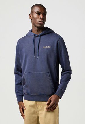 Mörkblå bomulls-Hoodie med framficka, justerbar dragsko och en liten broderad logotyp på bröstet. Slät textur.