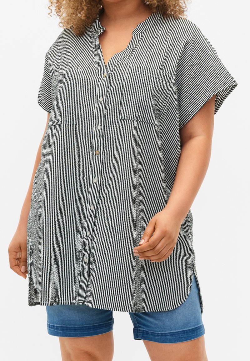 Black and white striped button-up shirt with a short collar, two front pockets, and rolled short sleeves; textured fabric with a loose fit.