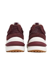 Un paio di sneakers in suede color bordeaux con suole spesse bianche e suole esterne in gomma marrone, viste da dietro con il brand "Pepe Jeans".